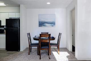 Model unit kitchen and dining area at Skyler Ridge with black appliances, wood dining tableand open flow.