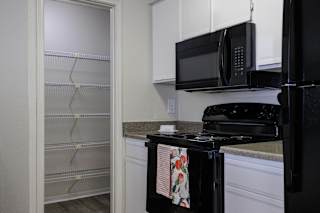A kitchen in a model unit at Skyler Ridge Complex, featuring black appliances, a sink, a refrigerator, and a stove.