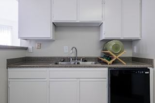 A model unit kitchen at Skyler Ridge Complex with black appliances, a sink, a refrigerator, and a stove.