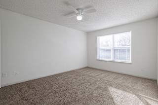 An empty bedroom in a model unit at Skyler Ridge Complex, featuring carpet and a large window with natural light.