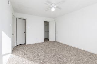 A model unit bedroom at Skyler Ridge Complex, empty with carpet and a window bringing in natural light.