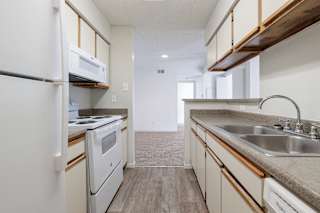 A model unit kitchen at Skyler Ridge Complex with white appliances, a sink, a refrigerator, and a stove.