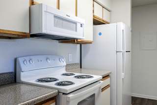 A model unit kitchen at Skyler Ridge Complex with white appliances, a sink, a refrigerator, and a stove.