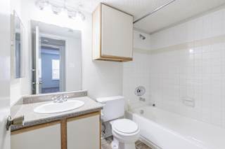A bathroom in a model unit at Skyler Ridge Complex, featuring a sink, a shower, and a mirror.