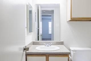 A bathroom in a model unit at Skyler Ridge Complex, featuring a sink, a shower, and a mirror.