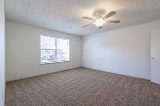 A model unit bedroom at Skyler Ridge Complex with carpeted floors and a window.