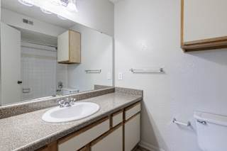 A bathroom in a model unit at Skyler Ridge Complex, featuring a sink, a shower, and a mirror.