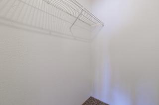 Clean, empty closet in a Skyler Ridge model unit with white walls and a hanging rail.