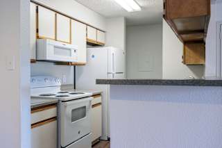 A model unit kitchen at Skyler Ridge Complex with white appliances, a sink, a refrigerator, and a stove.