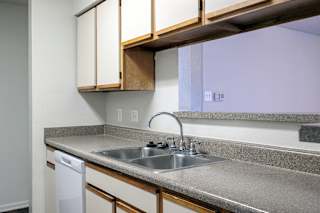 A model unit kitchen at Skyler Ridge Complex with white appliances, a sink, a refrigerator, and a stove.