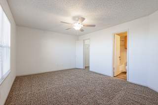 Spacious model bedroom at Skyler Ridge with carpet, a ceiling fan, and large windows.
