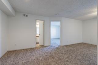 An empty living room in a model unit at Skyler Ridge Complex with large windows and plenty of natural light.