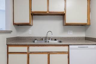 A kitchen in a model unit at Skyler Ridge Complex, featuring white appliances, a sink, and a dishwasher.