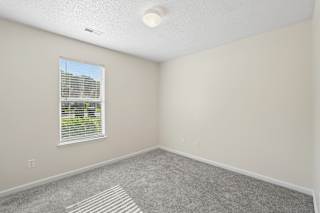 A room with a window and a striped rug on the floor.