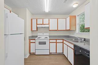 A kitchen with a white refrigerator and wooden cabinets.