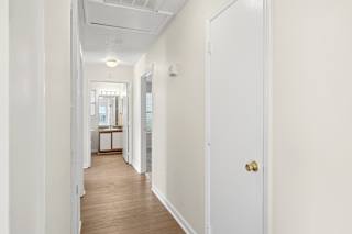 A long white hallway with a door on the right.