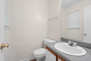 A bathroom with a toilet, sink, and mirror.