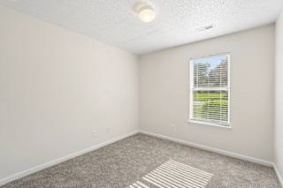 A room with a carpeted floor and a window with blinds.