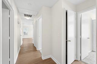 A long hallway with white walls and wood floors.