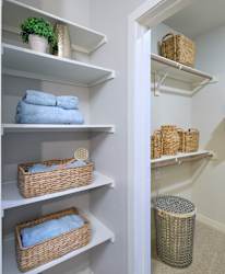 A white closet with baskets and towels.