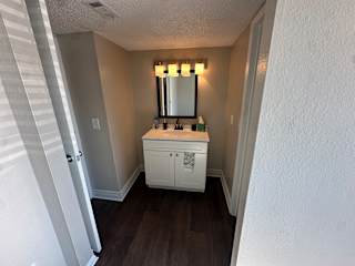 A white bathroom vanity with a mirror and lights above it.at Auburn Glen Apartments, Jacksonville