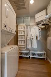 A laundry room with a washer and dryer and a rack of white robes. at One Foundry Way Apartments, St Louis, MO