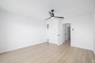 A room with a ceiling fan and wooden flooring.