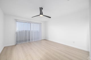A room with a ceiling fan and a window with blinds.
