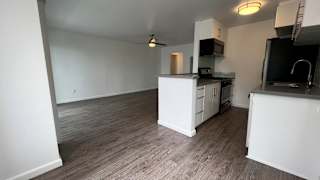 A kitchen with white cabinets and a wooden floor.