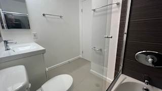 A white toilet is in a small bathroom with a sink and a shower.