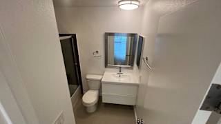 A small bathroom with a toilet, sink, and mirror.