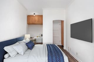 A bedroom with a bed, a lamp, a cabinet, and a door.