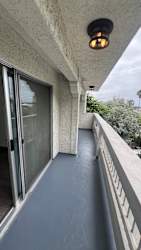 A balcony with a grey floor and a white railing.