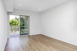 an empty living room with a sliding glass door to a balcony