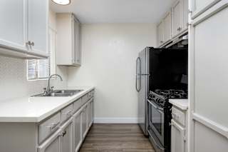 an empty kitchen with white cabinets and a black stove and refrigerator