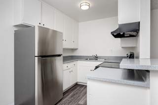 a kitchen with white cabinets and a stainless steel refrigerator