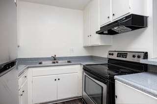 an empty kitchen with white cabinets and black appliances