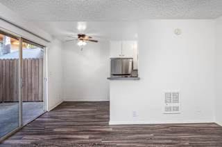 an empty living room with a ceiling fan and a sliding glass door