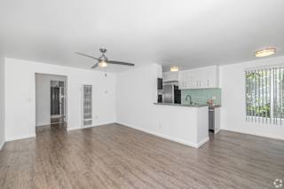 A spacious living room with a ceiling fan and hardwood flooring.