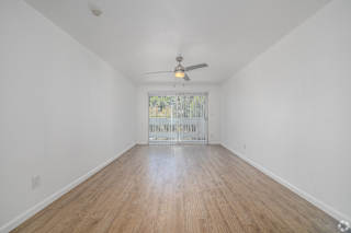 A room with a ceiling fan and wooden flooring.