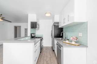 A kitchen with white cabinets and a green backsplash.