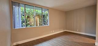 A room with a large window and wooden flooring.