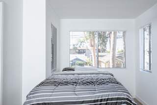 a small bedroom with a bed and a large window