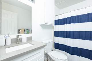 a white bathroom with a blue and white shower curtain