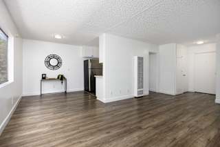 an empty living room and kitchen with white walls and wood flooring