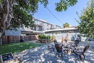 a backyard with a table and chairs and a tree