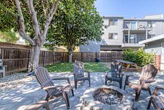 a backyard with a fire pit and chairs and a tree