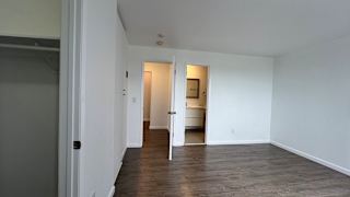 A room with white walls and wooden flooring with two doors.