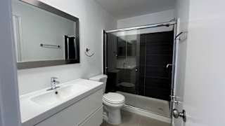 A white bathroom with a toilet, sink, and shower.