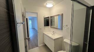 A white bathroom with a sink, mirror, and toilet.
